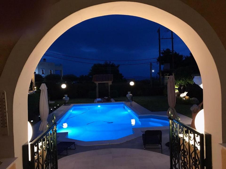 an archway leading to a swimming pool at night at Villa VS in Vathí