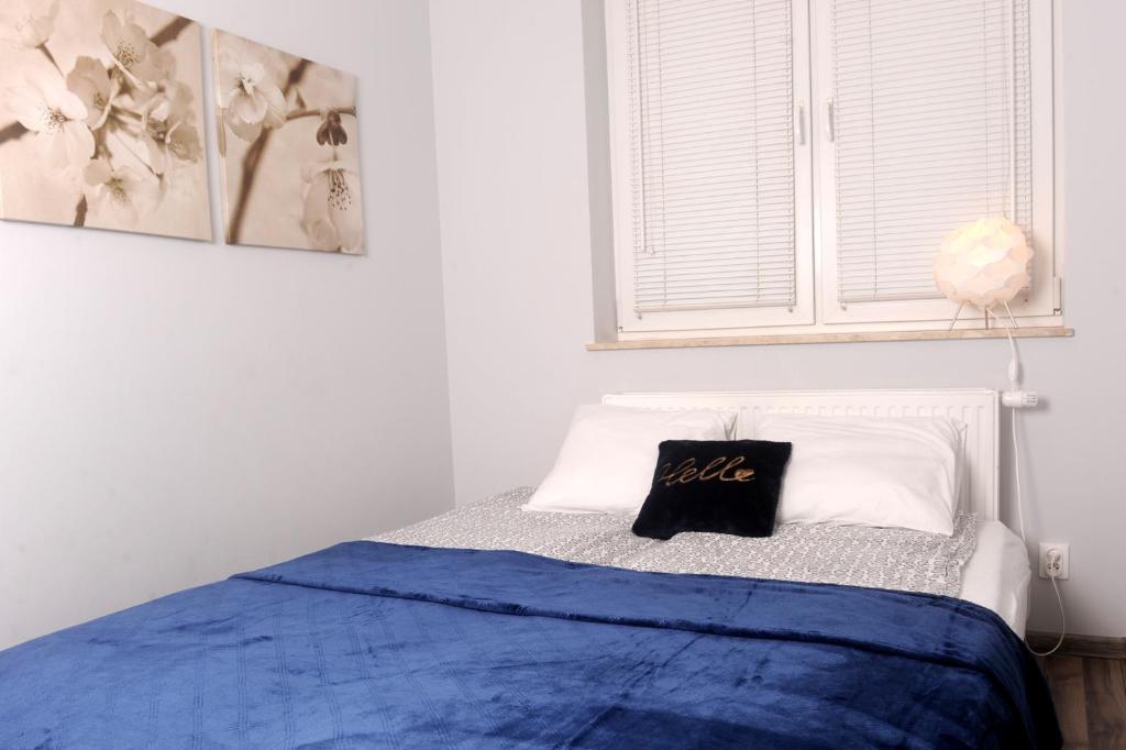 uma cama com um cobertor azul e uma almofada em Apartament Ster Kołobrzeg em Kolobrzeg