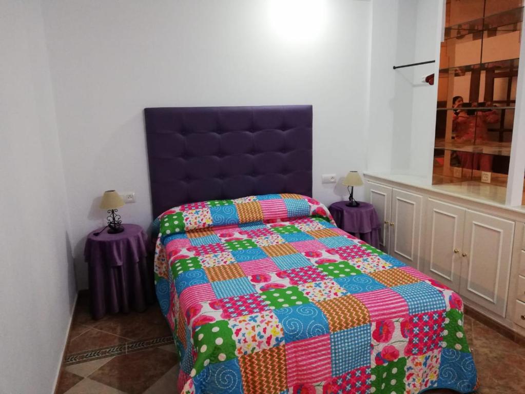 ein Schlafzimmer mit einem Bett mit einer bunten Decke in der Unterkunft HABITACION LILA in Barbate