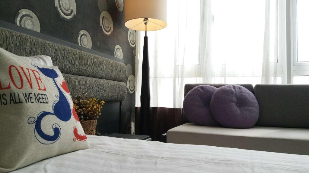 a bedroom with a bed with purple pillows and a couch at Twin Galaxy Residences in Johor Bahru