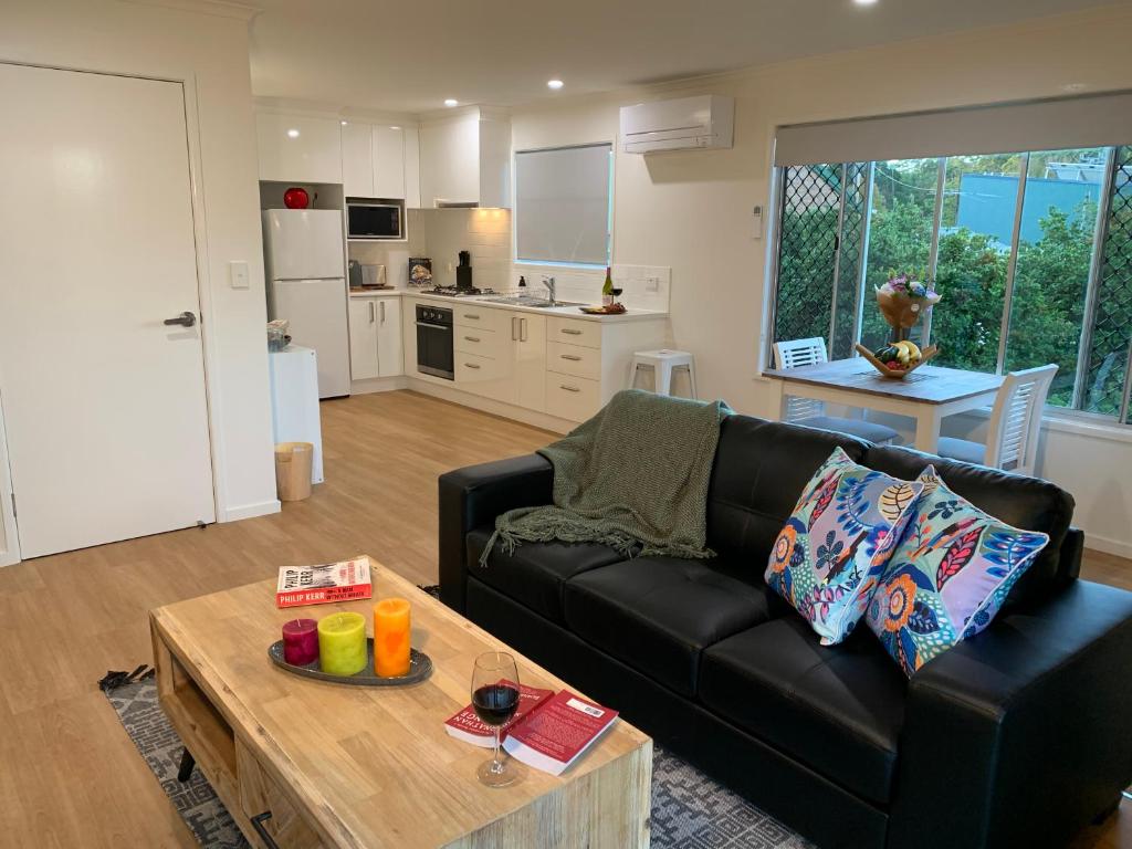 a living room with a black couch and a table at Little Bank House in Mount Tamborine