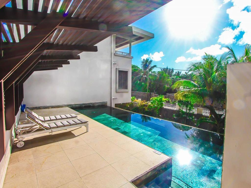 a house with a swimming pool next to a house with a staircase at Nitzana Residences & Restaurant in Pereybere