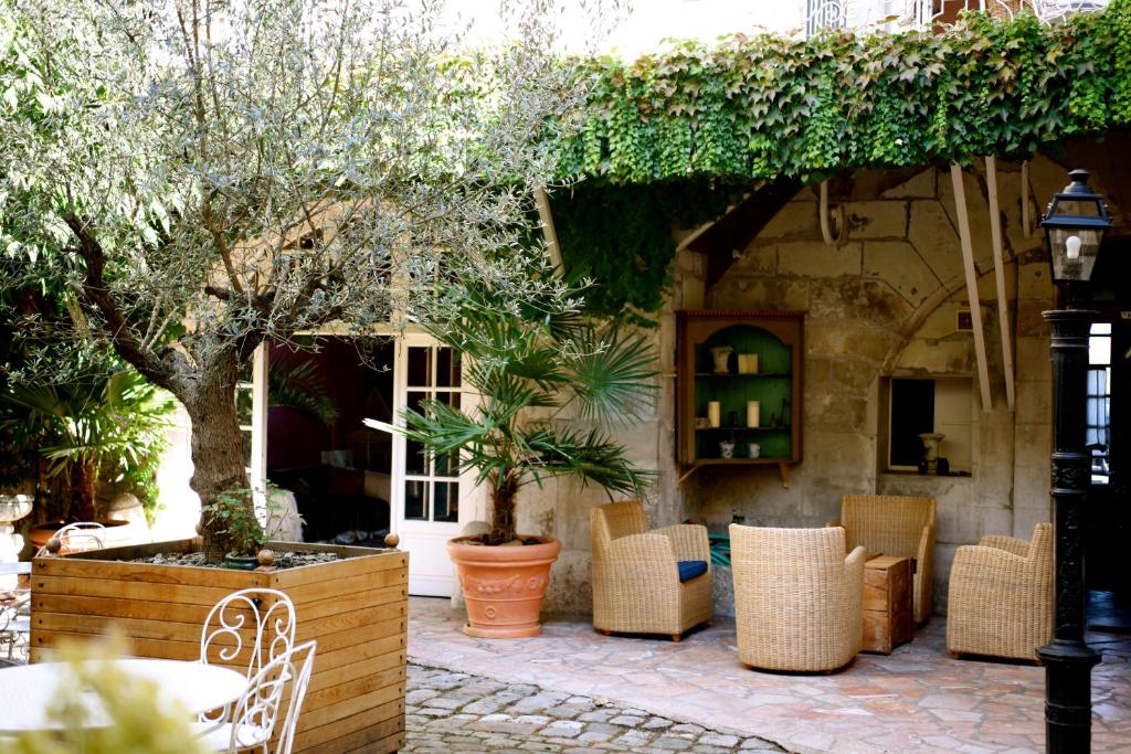 un patio avec des chaises et des tables ainsi qu'un bâtiment dans l'établissement Le Patio & Spa, à Saumur