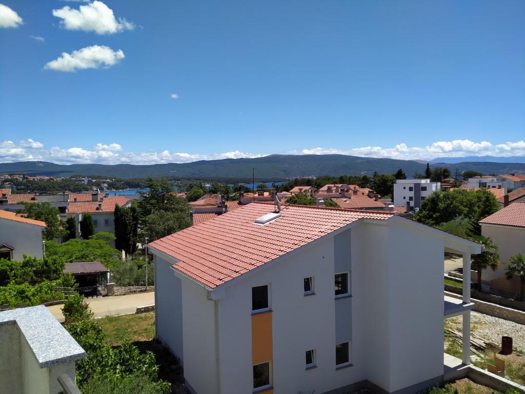 a white building with a red roof with mountains in the background at Apartment Morozin in Krk