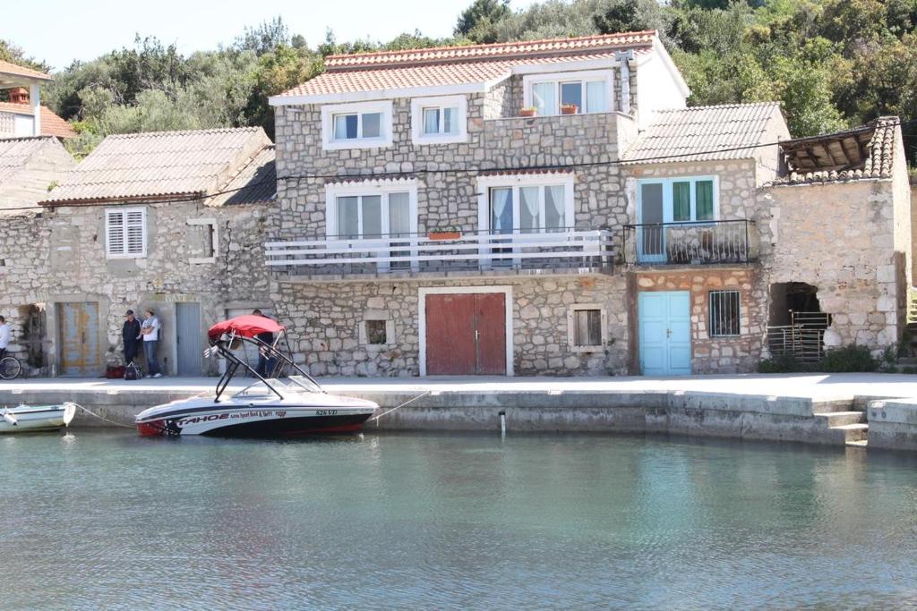a man on a boat in the water next to a building at Apartment Mali Iz 6163a in Iž Mali