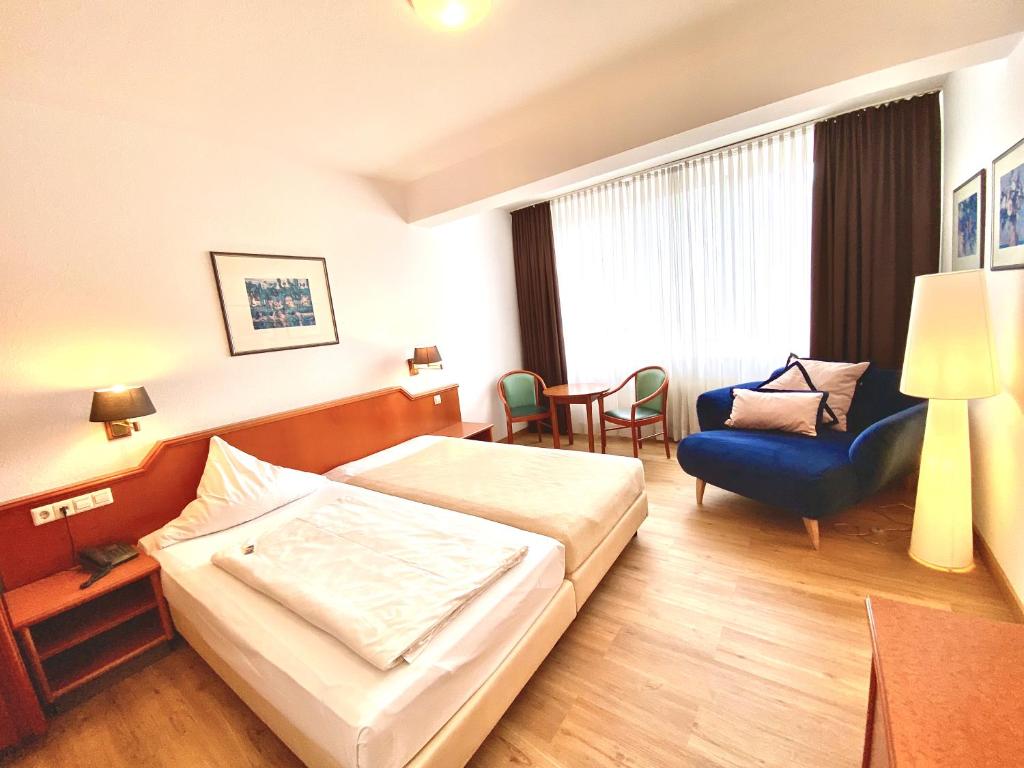 ein Hotelzimmer mit einem Bett und einem Stuhl in der Unterkunft Hotel Garni Rebgarten in Ravensburg