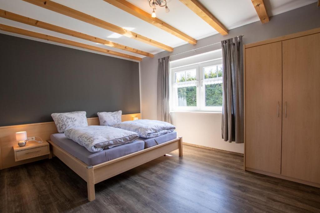 Schlafzimmer mit einem Bett und einem Fenster in der Unterkunft Apartmenthaus Djuren in Dornum