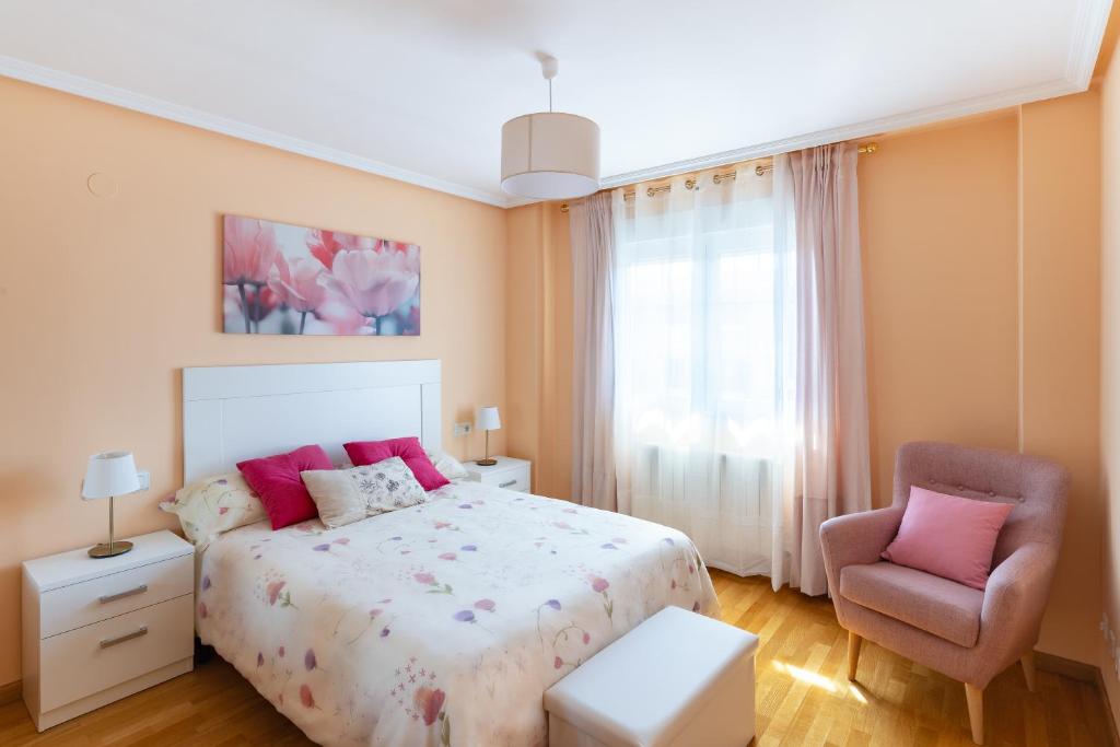 een slaapkamer met een bed en een stoel bij Housingleón - Parque de las Artes con Garaje in León