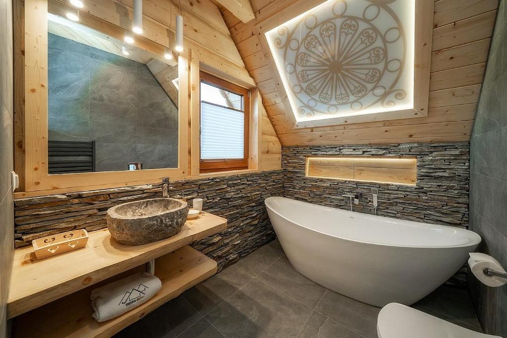 a bathroom with a tub and a sink in a cabin at "Osada Guty" - Domki z Jacuzzi - Szaflary in Szaflary