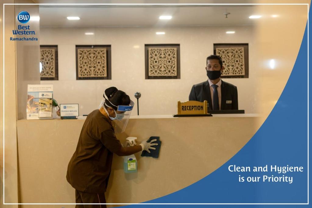 a man wearing a face mask standing at a reception desk at Best Western Ramachandra in Visakhapatnam