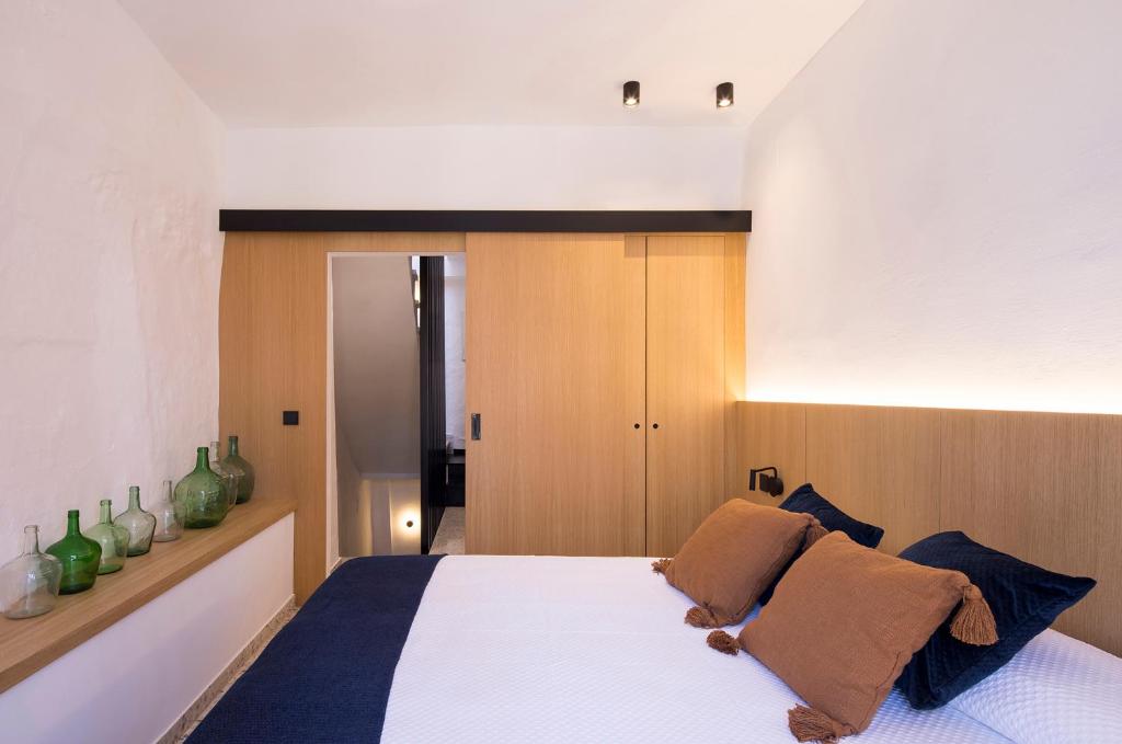 una camera da letto con un grande letto bianco con cuscini marroni di LA ALMACERÍA DE ANTEQUERA ad Antequera