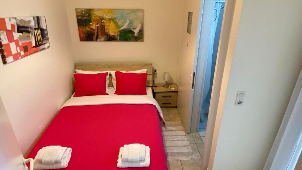 een kleine kamer met een bed met rode kussens bij Patras Port apartment in Patra