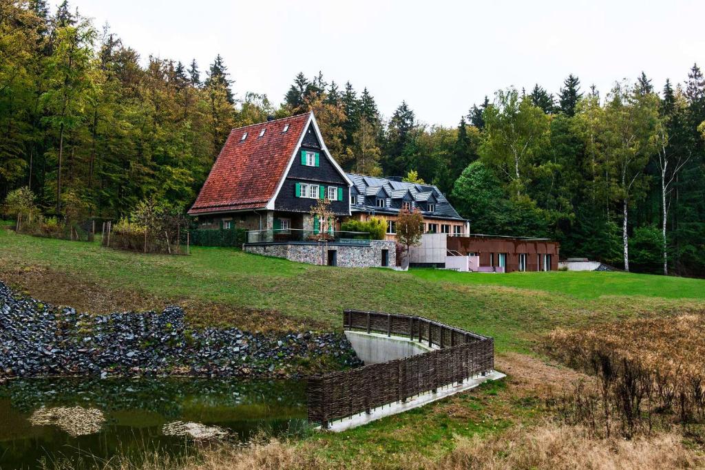 a house on a hill with a pond in front of it at Jagdschloss Windenhütte in Thale