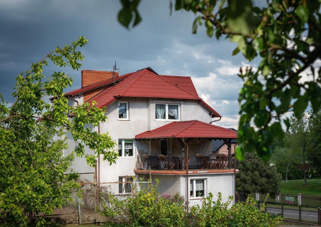 uma grande casa branca com um telhado vermelho em Agroturystyka Gawryś pokoje em Sasino