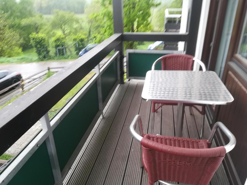 two chairs and a table on a balcony at Ferienwohnung Ziegelbergblick in Jockgrim