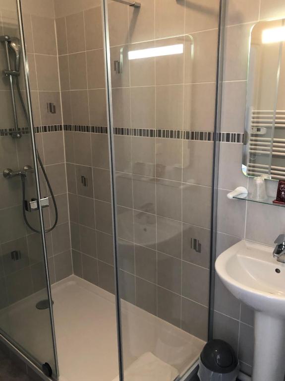 a shower with a glass door next to a sink at Crystal Hotel in Royan