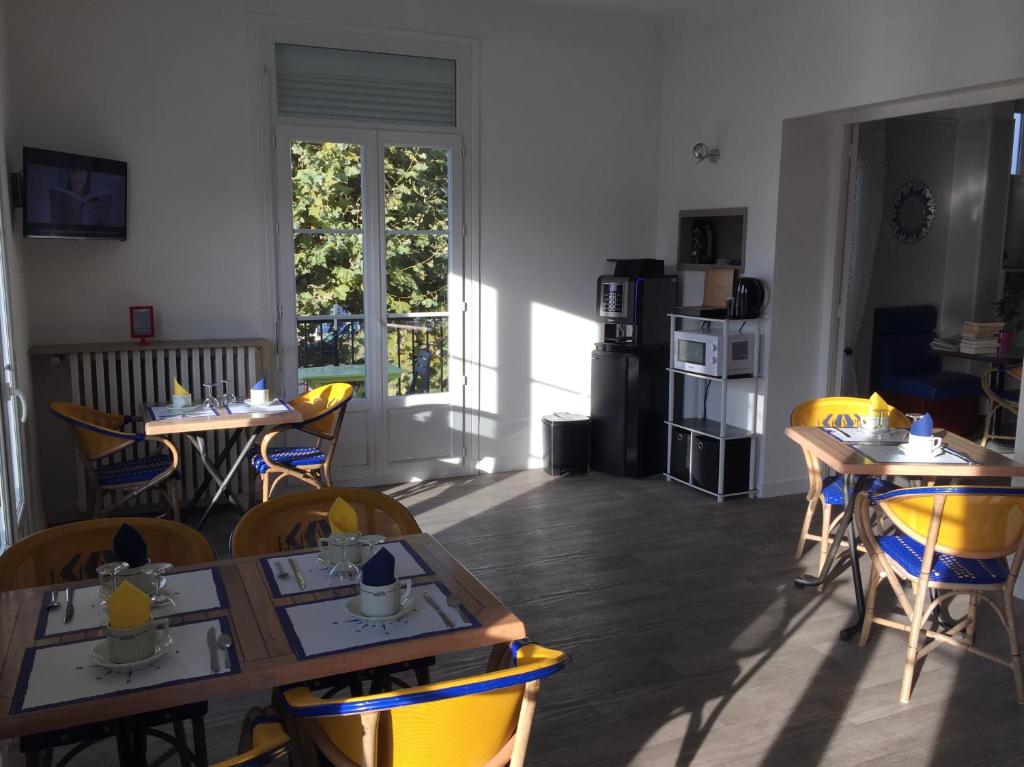 a dining room with tables and yellow chairs at Crystal Hotel in Royan