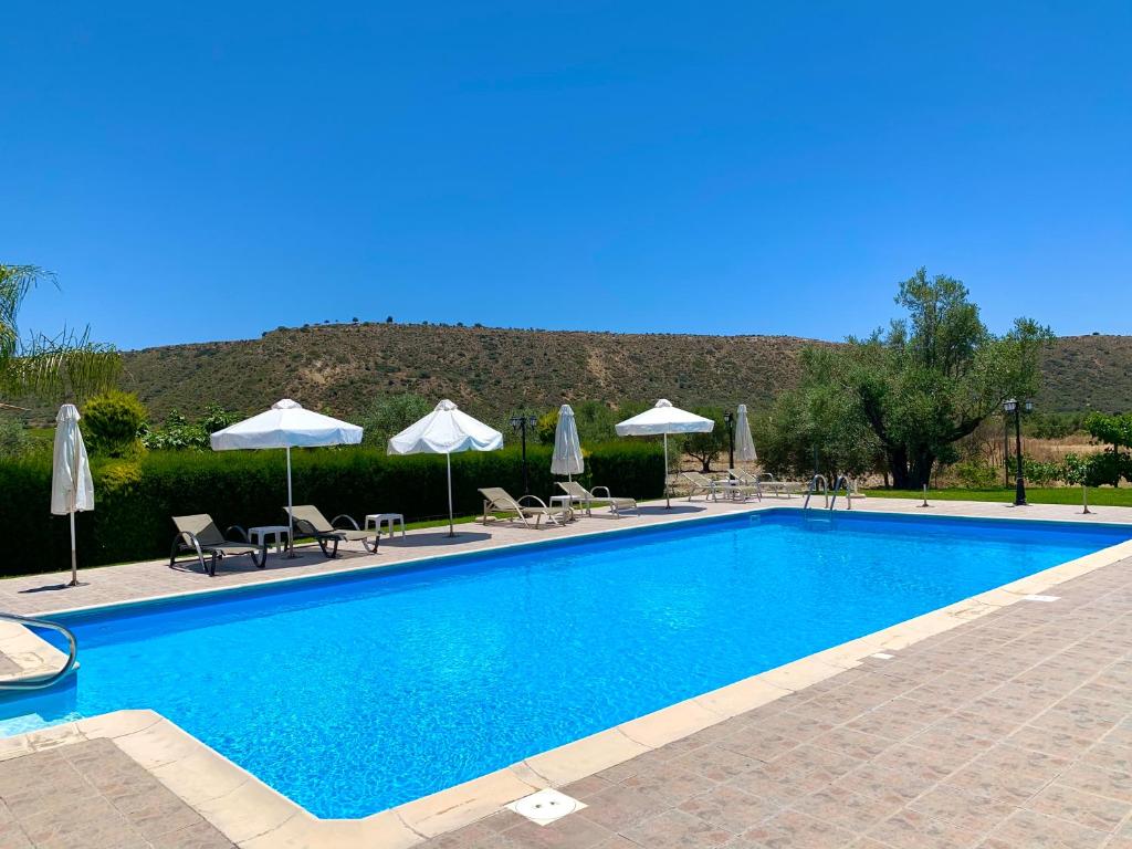 a swimming pool with chairs and umbrellas at Himonas Apartments in Pissouri