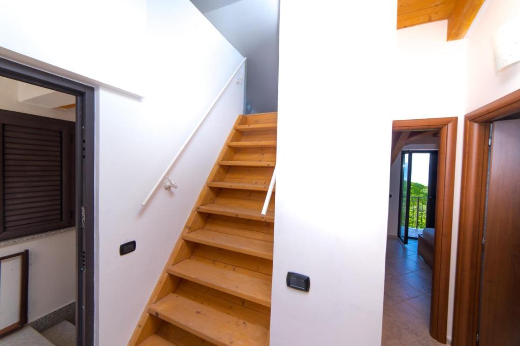 una escalera en una casa con paredes blancas y suelo de madera en Residence Fortunato, en Policastro Bussentino