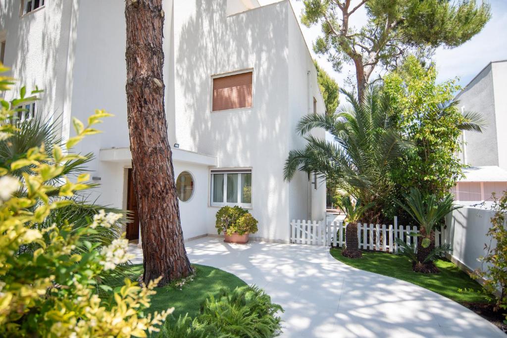 una casa blanca con un árbol en el patio en Blu Sun Apartment in Complesso Riva del Sole, en Giovinazzo