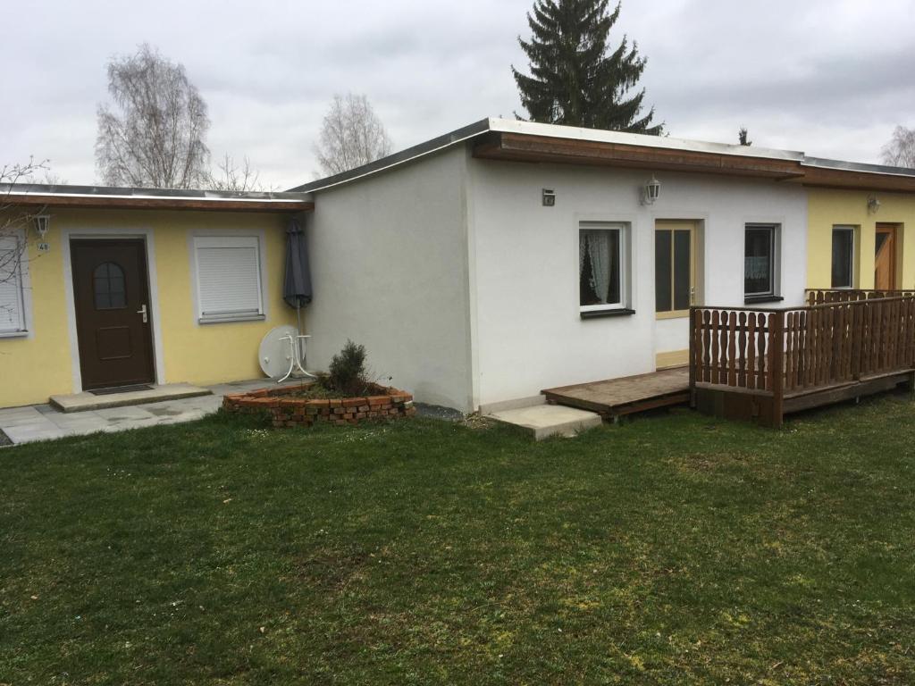 Casa blanca pequeña con porche y patio en Ferienhaus 47 am Zeulenrodaer Meer, en Zadelsdorf