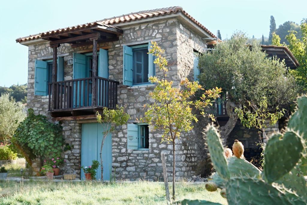 Cette maison en pierre dispose de fenêtres bleues et d'un balcon. dans l'établissement Rizes, à Psárion