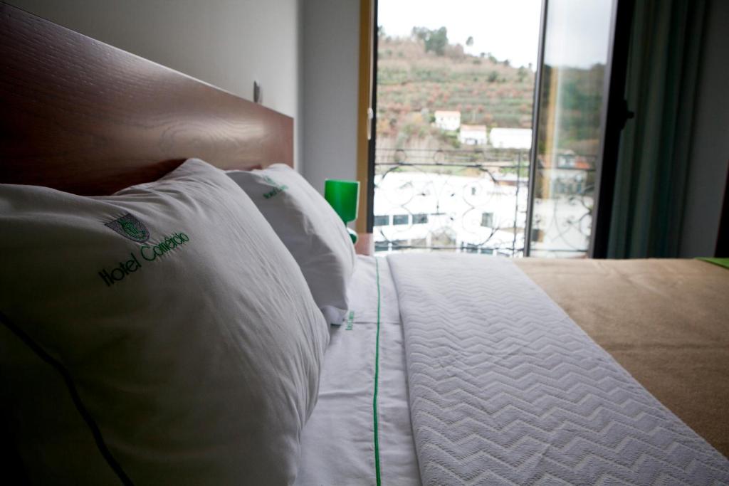 uma cama com uma almofada branca e uma janela em Hotel Comércio em Resende