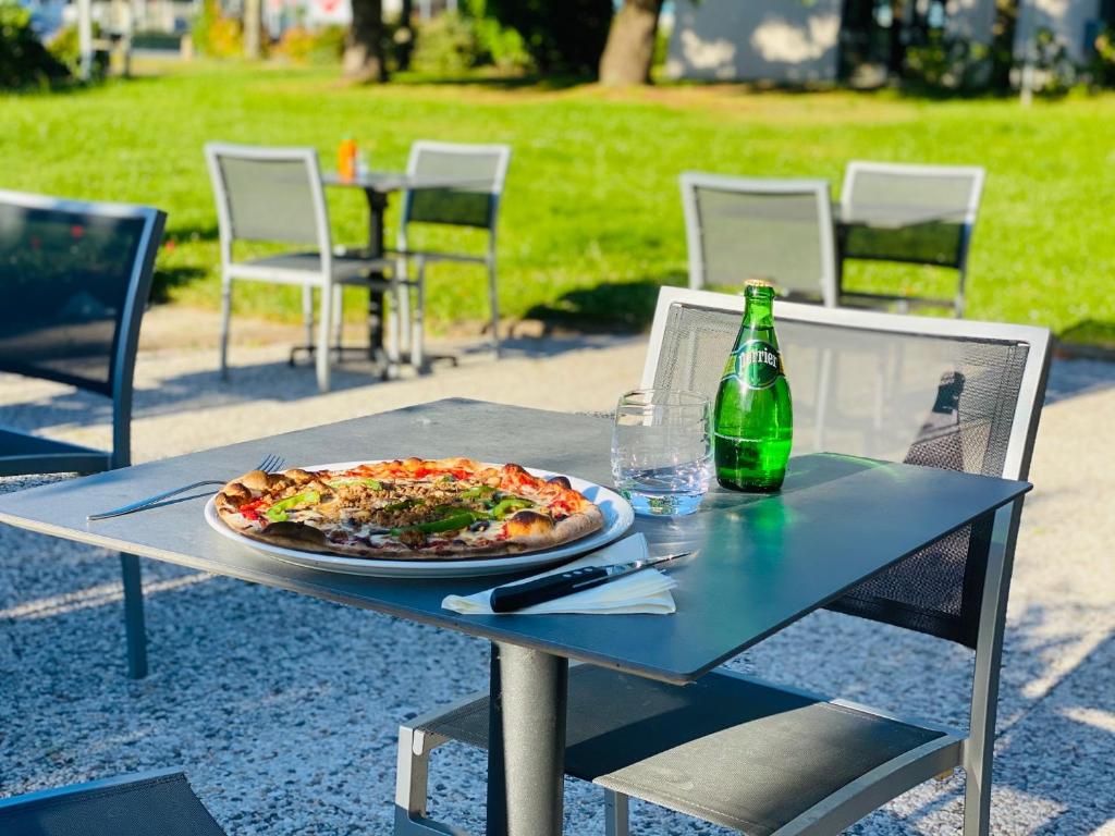 a pizza sitting on a table with a bottle of beer at Kyriad Hotel Meaux in Meaux