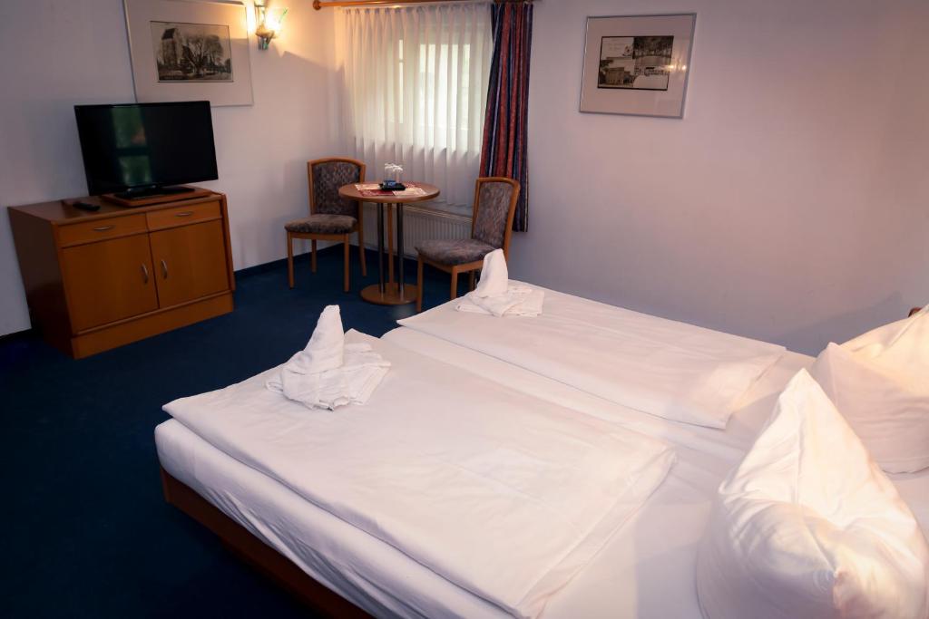 a hotel room with a large white bed and a television at Börse Coswig in Coswig