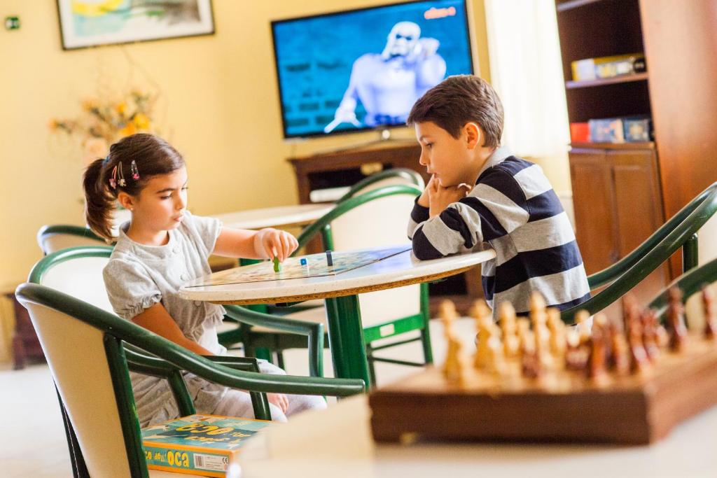 duas crianças sentadas numa mesa a jogar xadrez em Hotel Candido em Diano Marina