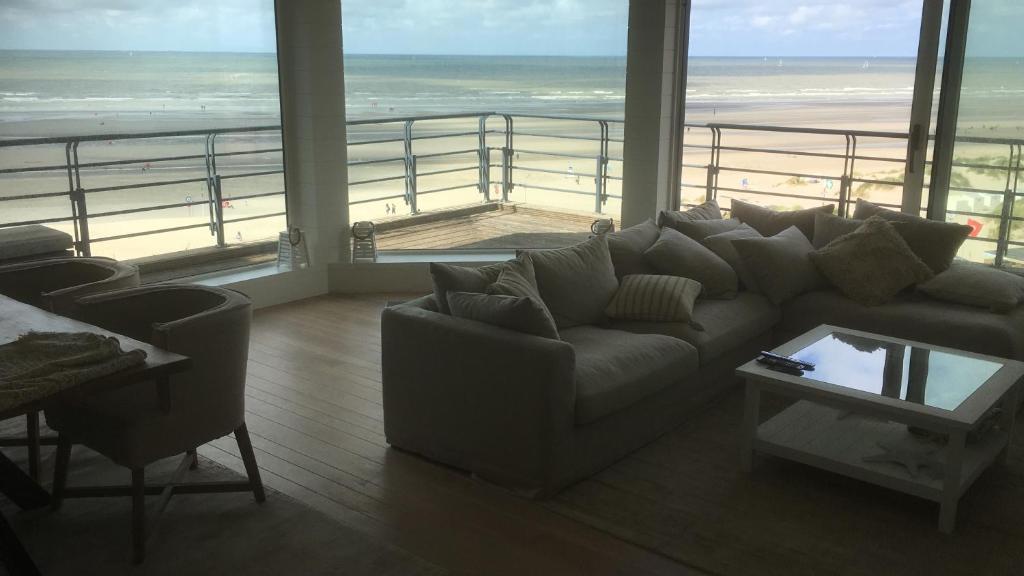 salon z kanapą i widokiem na plażę w obiekcie Oostduinkerke Long Island w mieście Koksijde