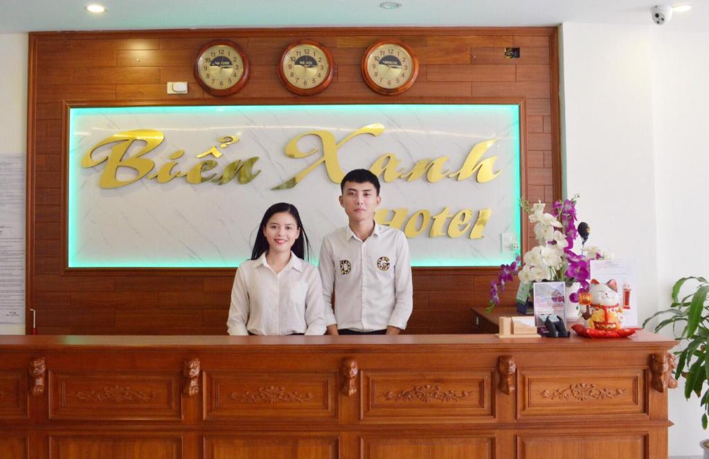 un homme et une femme debout derrière un bureau dans l'établissement Biển Xanh Hotel Quy Nhơn, à Quy Nhơn