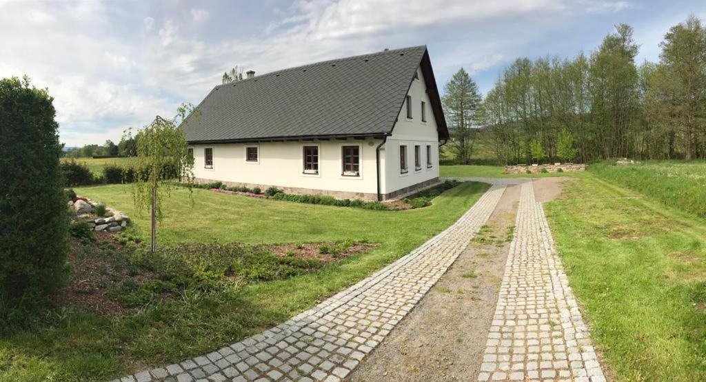 a white house with a black roof and a brick road at Ubytování Lipka in Králíky