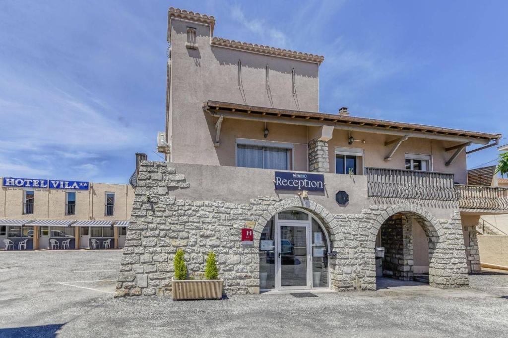 a hotel with a stone building with an entrance at Hôtel Vila in Frontignan