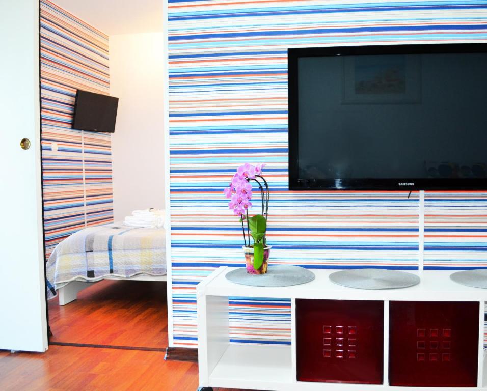 ein Wohnzimmer mit einem TV an einer gestreiften Wand in der Unterkunft Apartament Saturn Sophie By The Sea in Saturn