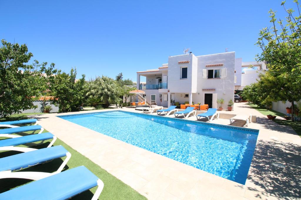 eine Villa mit einem Pool und Liegestühlen in der Unterkunft Villa Sunset - San Antonio Bay in Cala de Bou