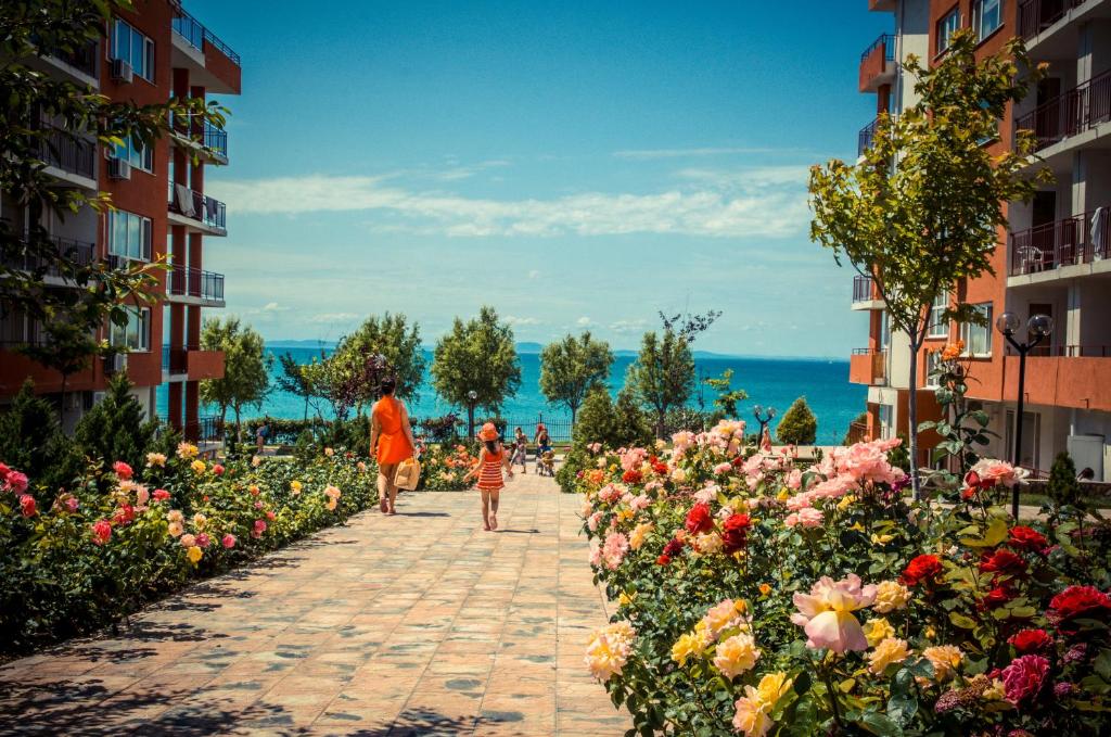 a woman and a child walking down a sidewalk with flowers at Marina View Fort Beach in Sveti Vlas