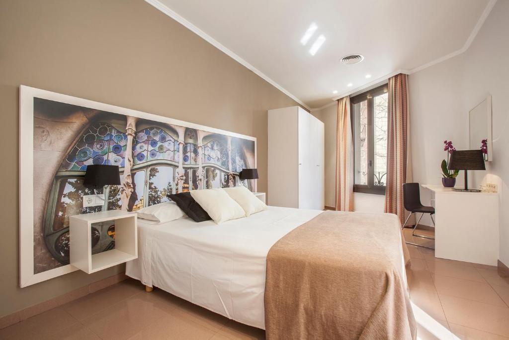 a bedroom with a white bed with a painting on the wall at BCNGOTIC 11 in Barcelona