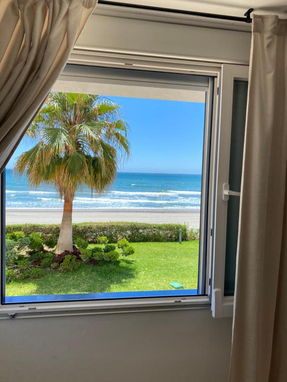une fenêtre avec vue sur un palmier et l'océan dans l'établissement Torrox beach, à Torrox Costa