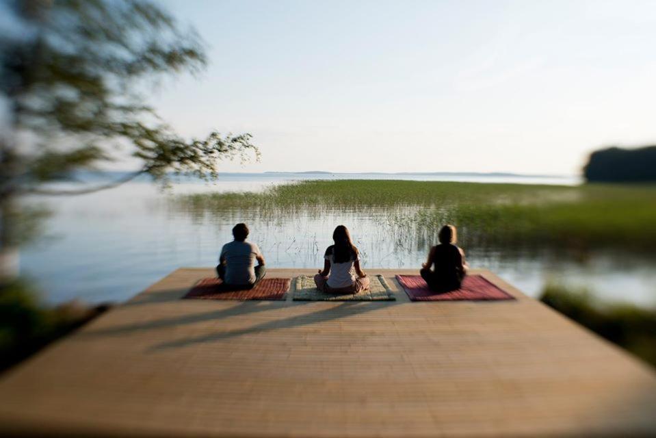 three people sitting on a dock near the water at Utula Nature Retreat in Ruokolahti