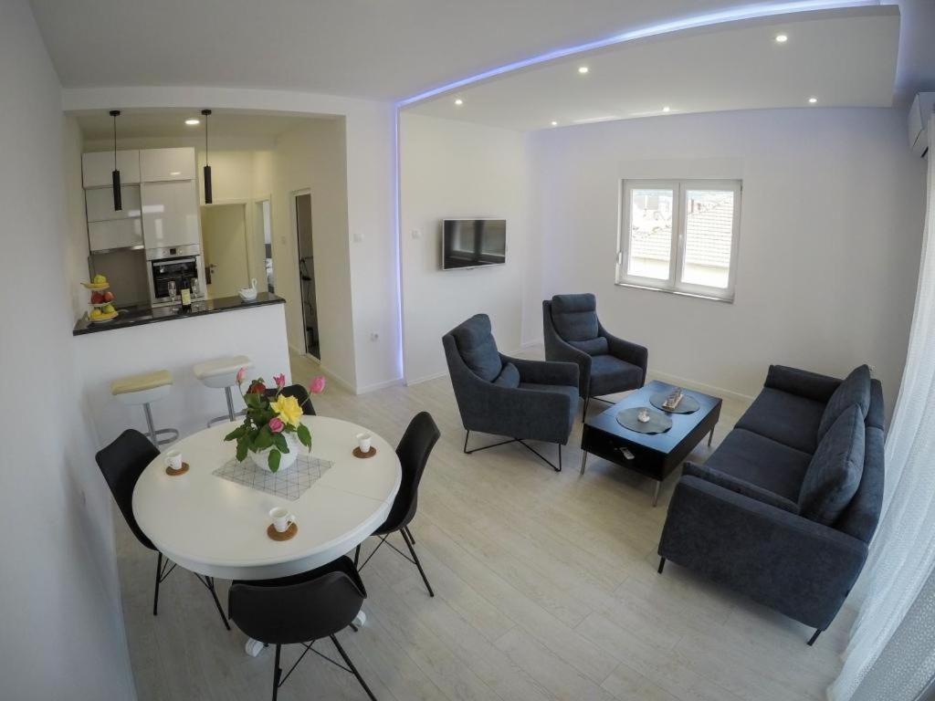 Il comprend un salon avec une table et des chaises ainsi qu'une cuisine. dans l'établissement Apartments Tila, à Trebinje