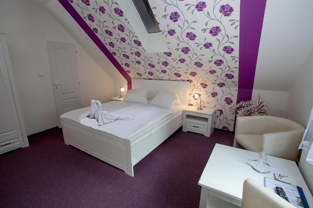 Dormitorio pequeño con cama y pared púrpura en Wellness penzion Harmonie Rohanov, en Prachatice
