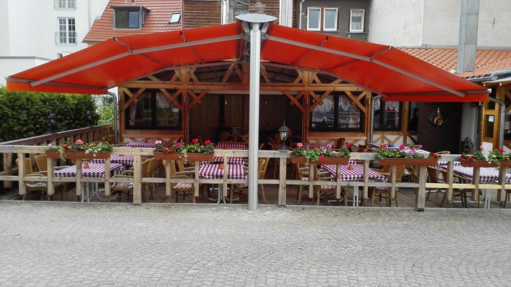 a restaurant with tables and chairs under a red umbrella at Südtiroler Stubn Café und Restaurant in Arnstadt