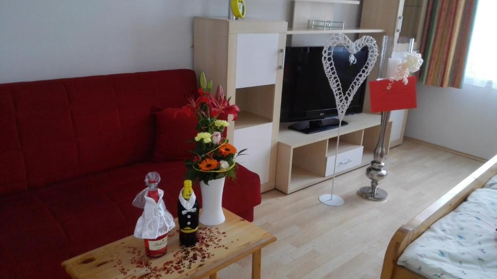 a living room with a red couch and a table with flowers at Südtiroler Stubn Café und Restaurant in Arnstadt