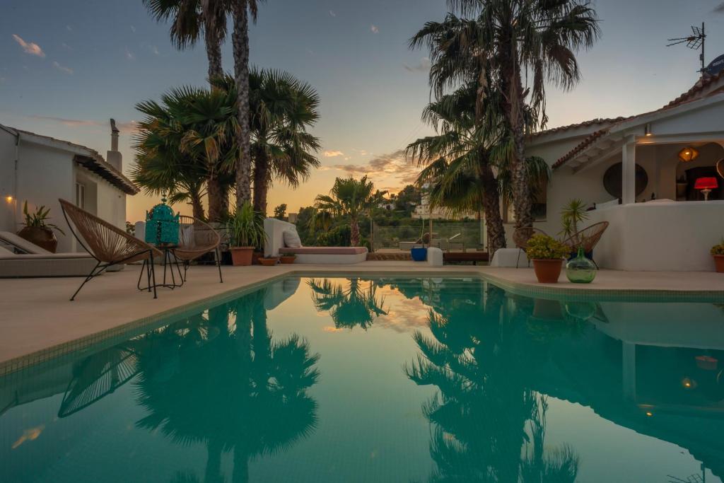 a house with a swimming pool with palm trees at Caballito de Mar in Moraira