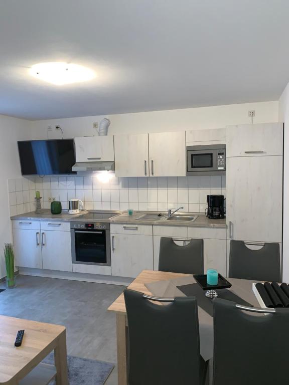 a kitchen with white cabinets and a table with chairs at Ferienhaus Ankerweg an der Seehundstation in Norddeich