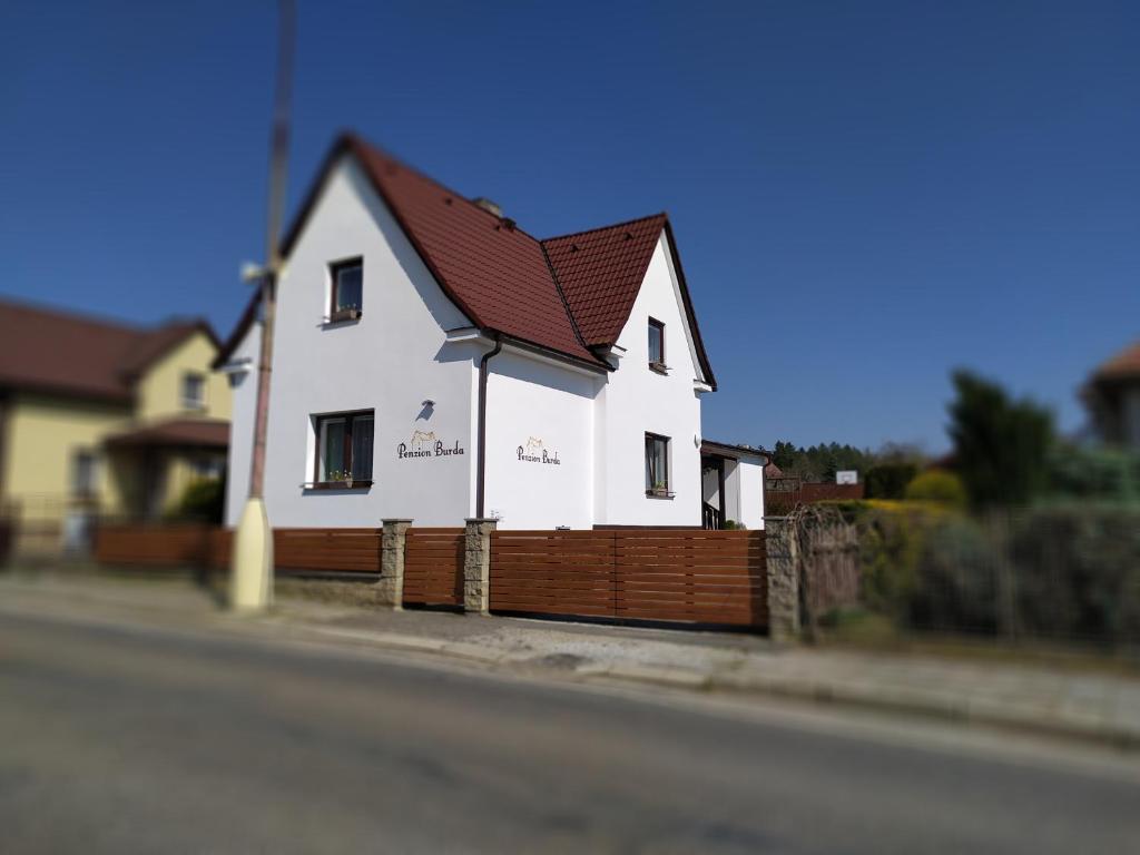 a white house with a wooden fence on the side of a street at Penzion Burda in Sepekov