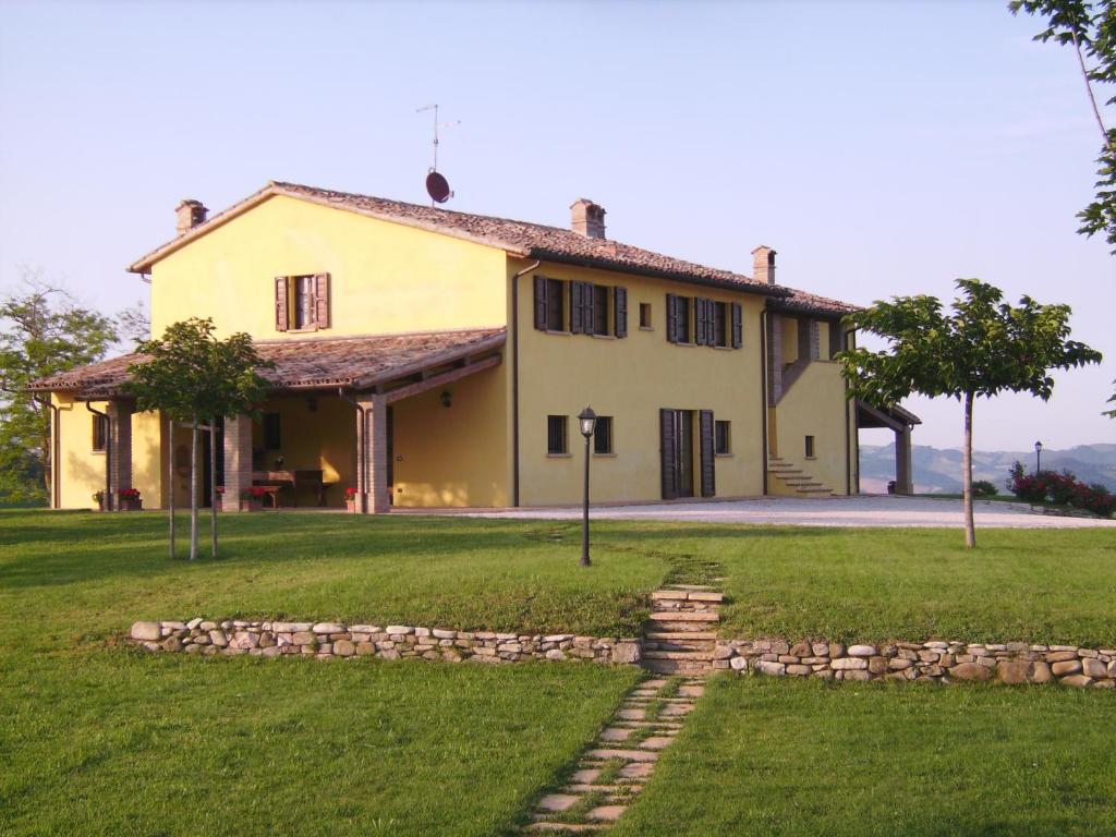 una grande casa gialla con un prato di Sant'Angiolino a Urbania