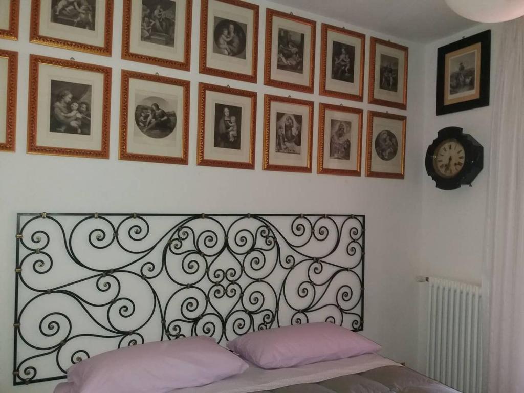 Casa Intignano - Camera con bagno e portico vista lago في تريميزو: غرفة نوم مع اللوح الأمامي والصور على الحائط