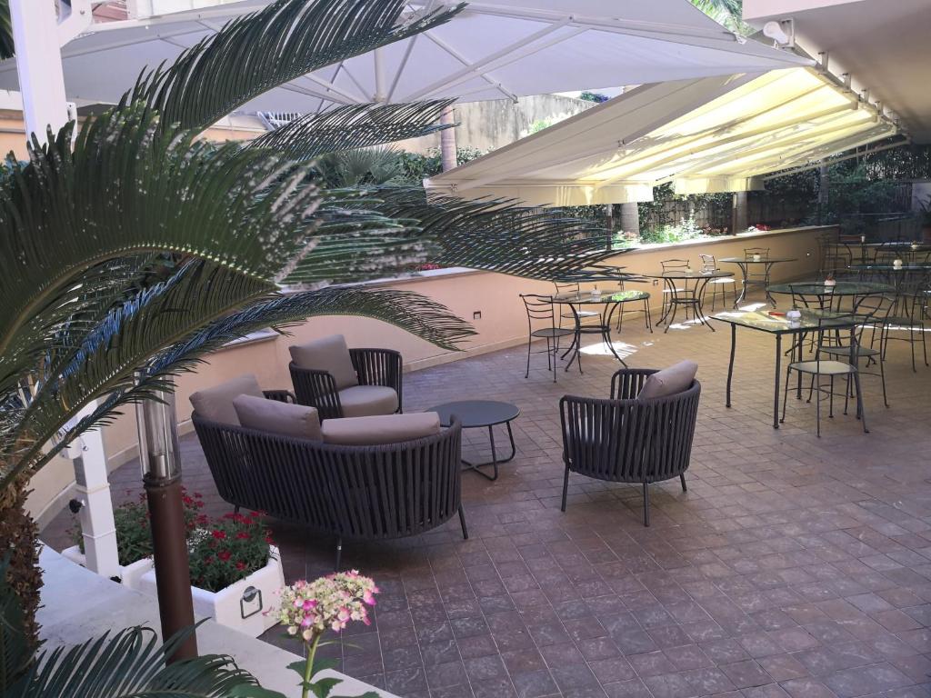 a patio with chairs and tables and umbrellas at Artemis Hotel in Cefalù